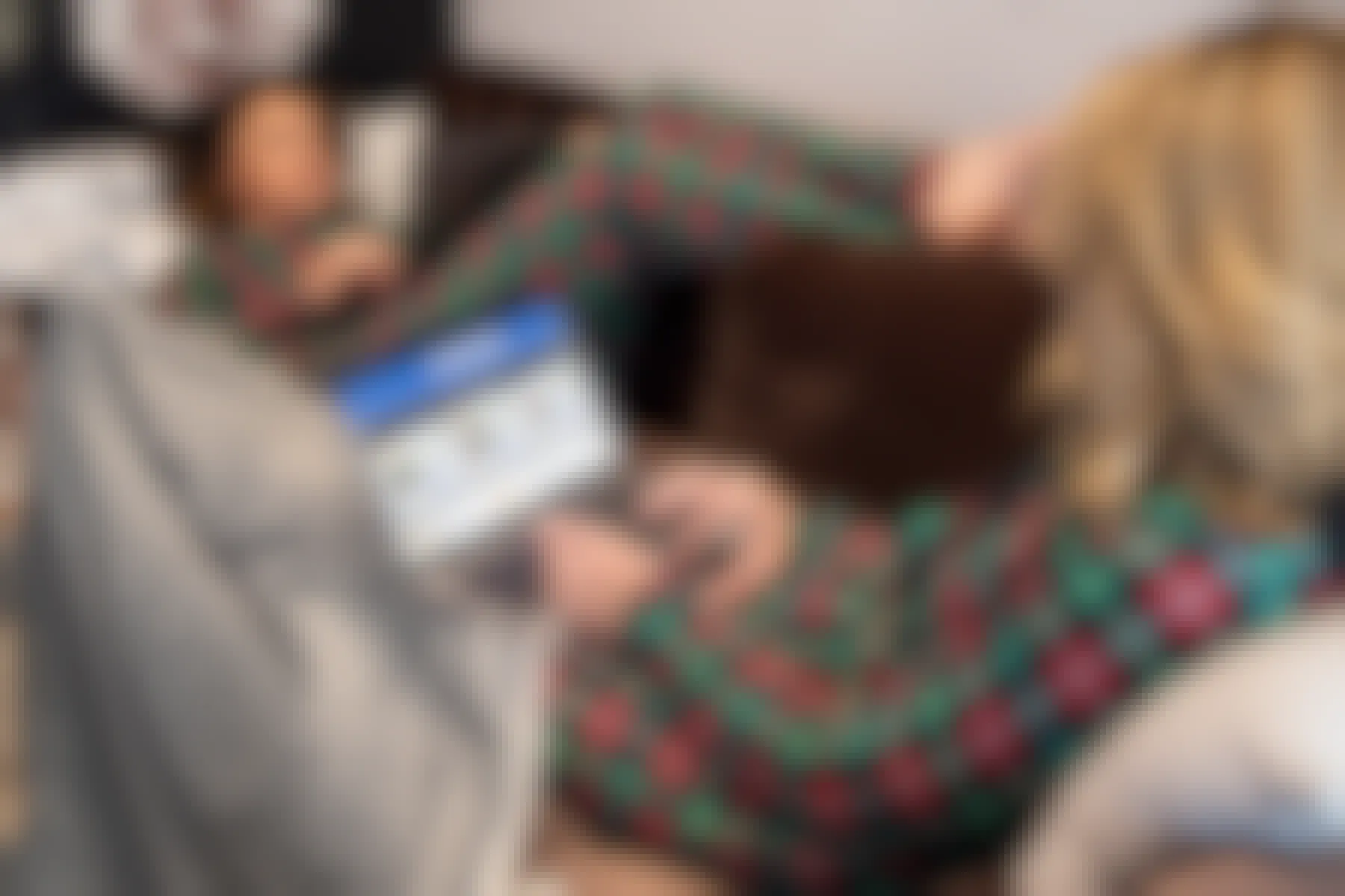Two people sitting on a couch together, each looking at their laptops, one of their screens facing forward displaying the Walmart.com deals for laptops