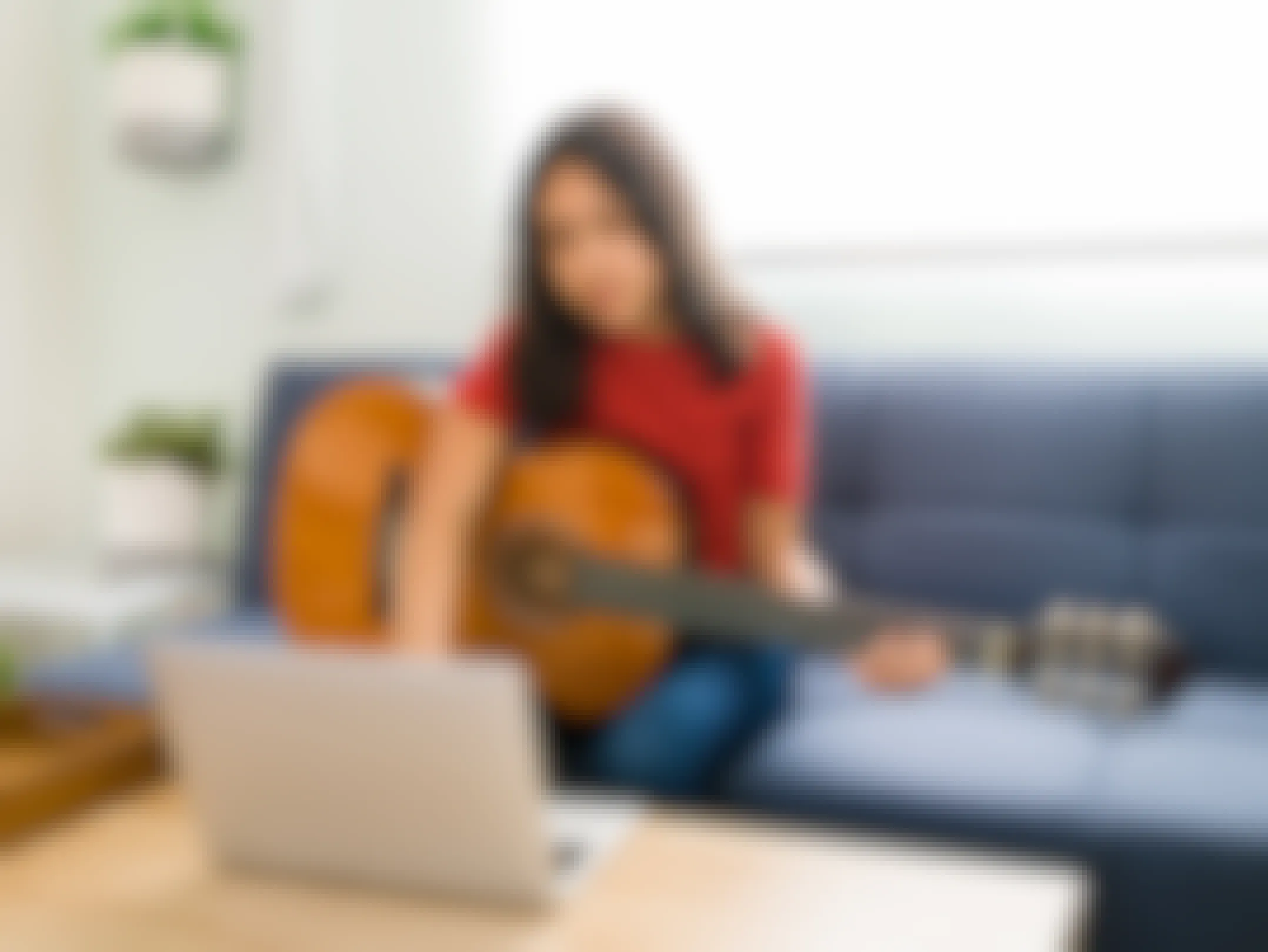 gifts for teens - A teen playing guitar and looking at a laptop