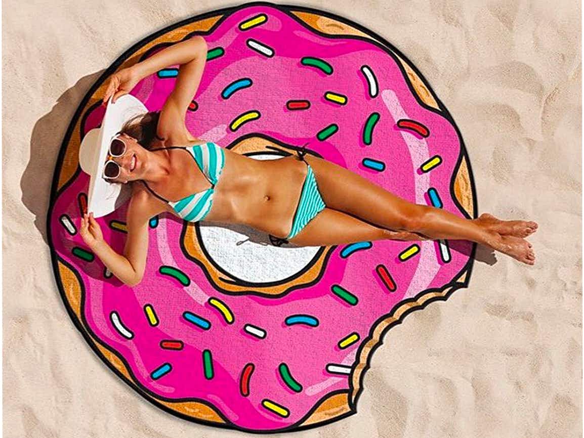 gifts for teens - A person laying on a beach towel shaped like a doughnut with sprinkles