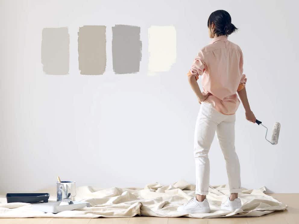 person painting different neutral swatches onto wall