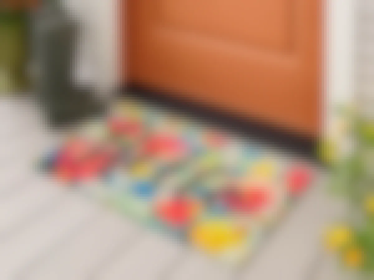 A welcome mat outside of. front door that says "Hello" with floral pattern