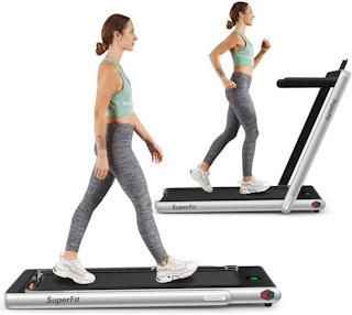 A person using a GoPlus 2-in-1 Folding Treadmill on a white background