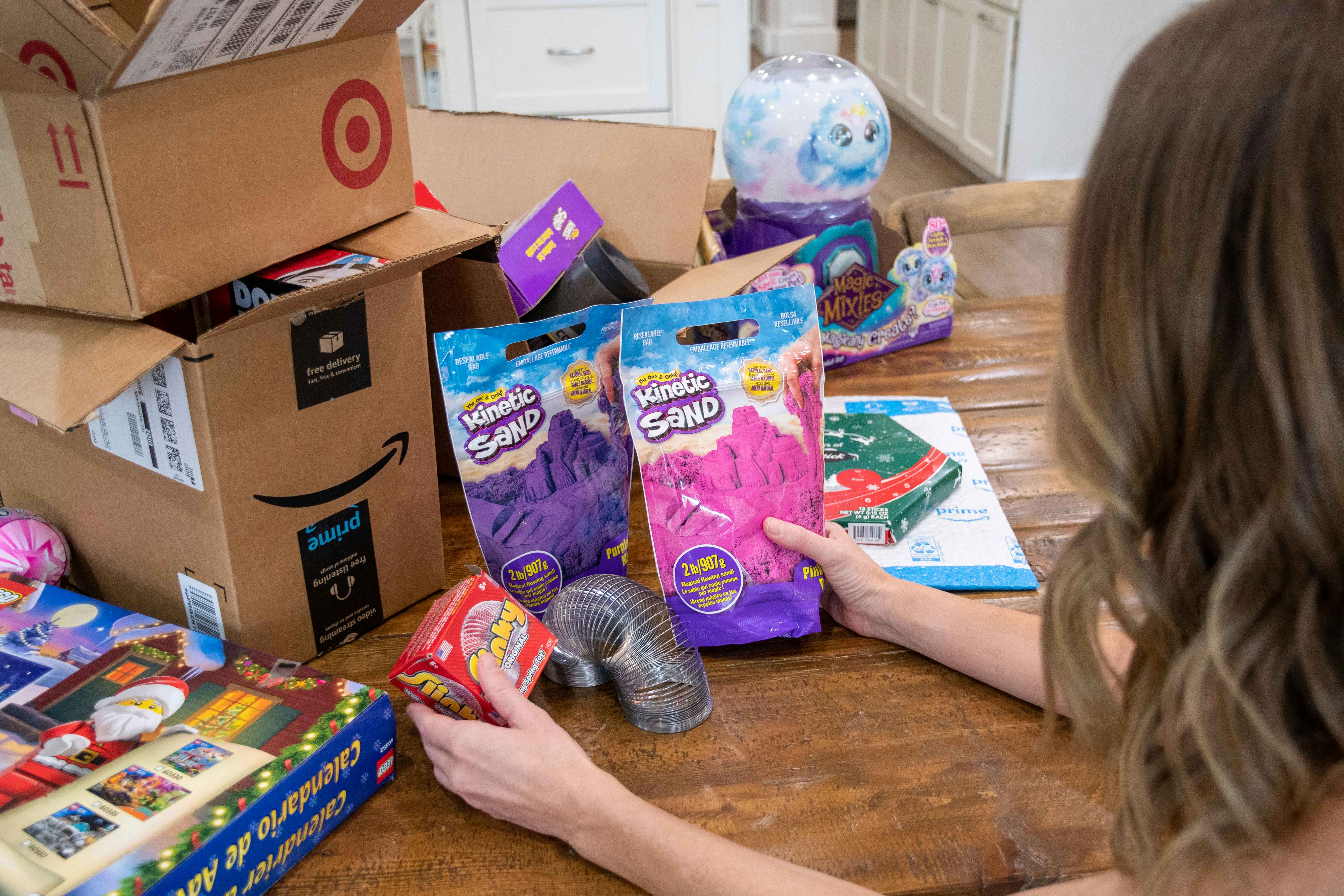 a woman sorting through toys next to open amazon and target shipping boxes