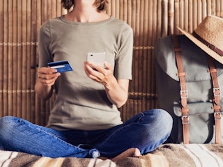 person booking travel deals on phone with card
