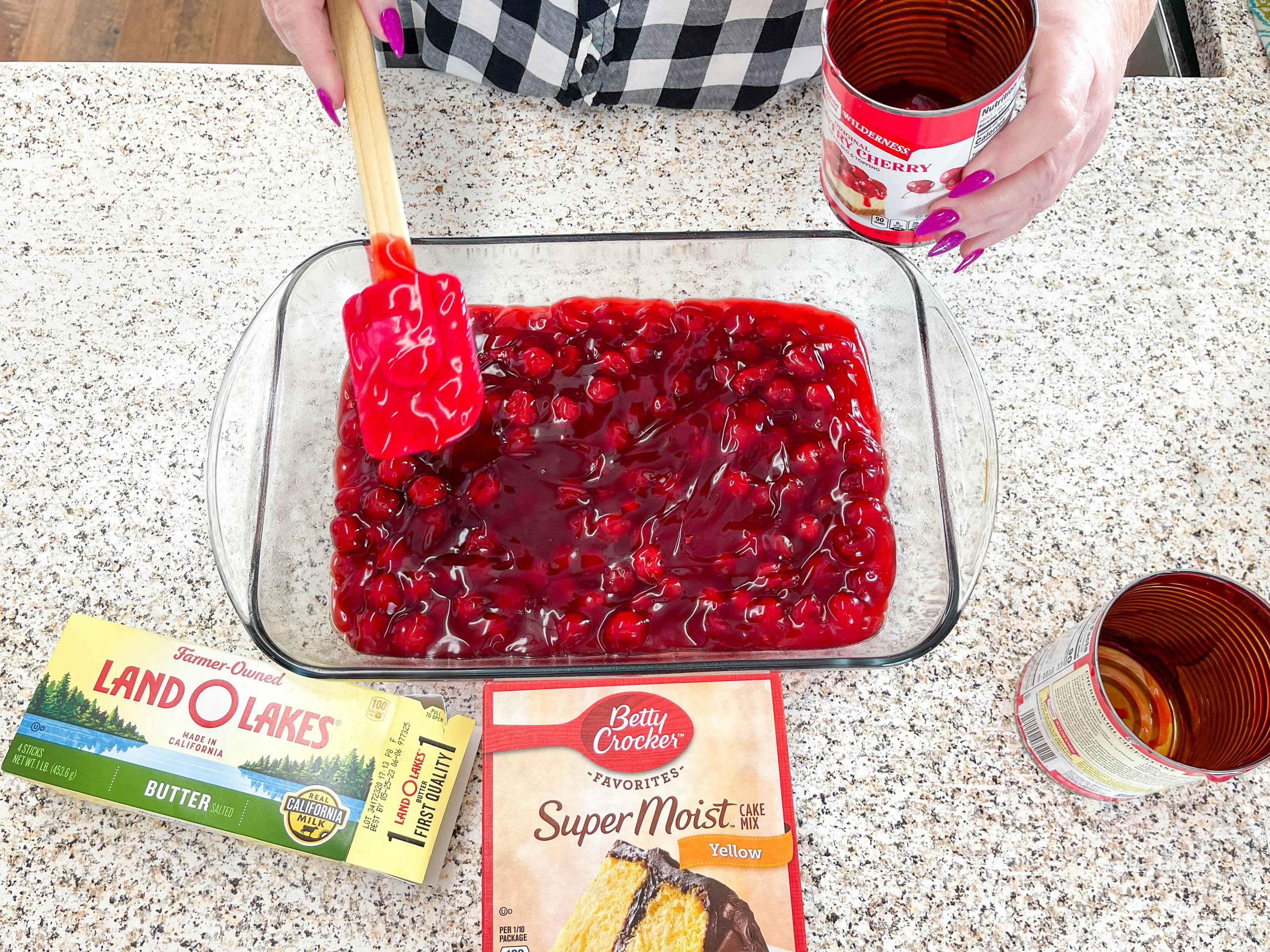 someone spreading canned cherry pie mix to make a dump cake 
