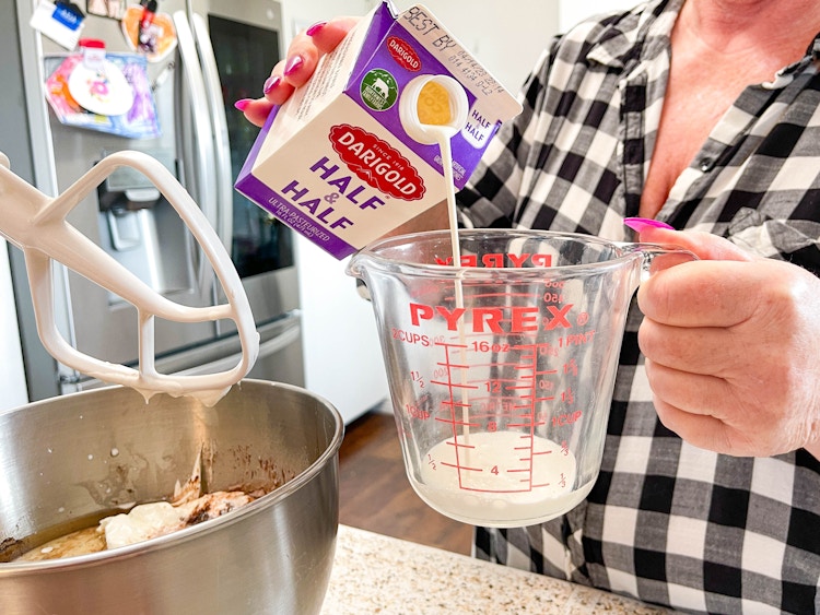 a person pouring half and half in a measuring cup 