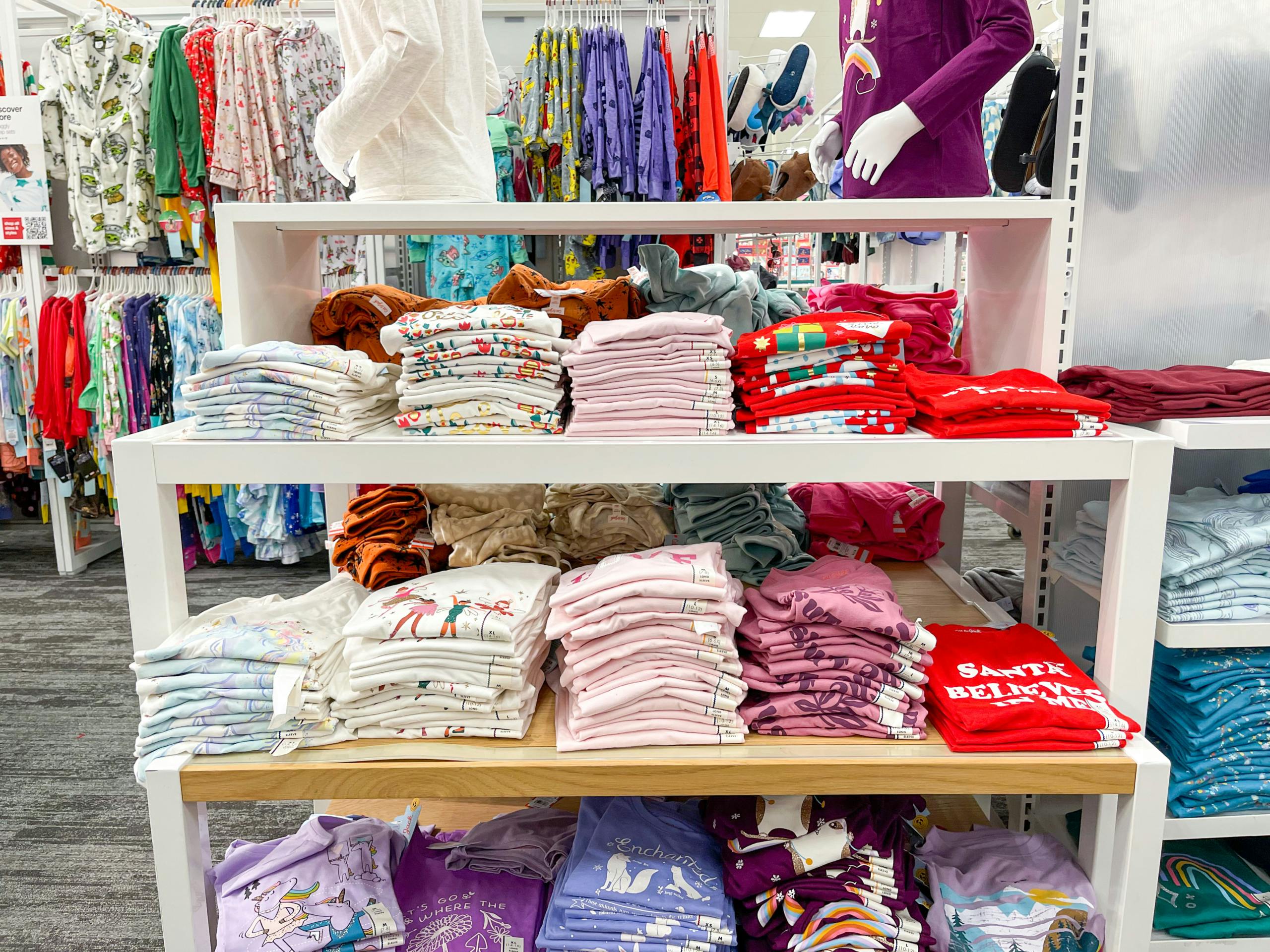 A variety of Cat and Jack long sleeved shirts folded and sitting on a store display shelf.