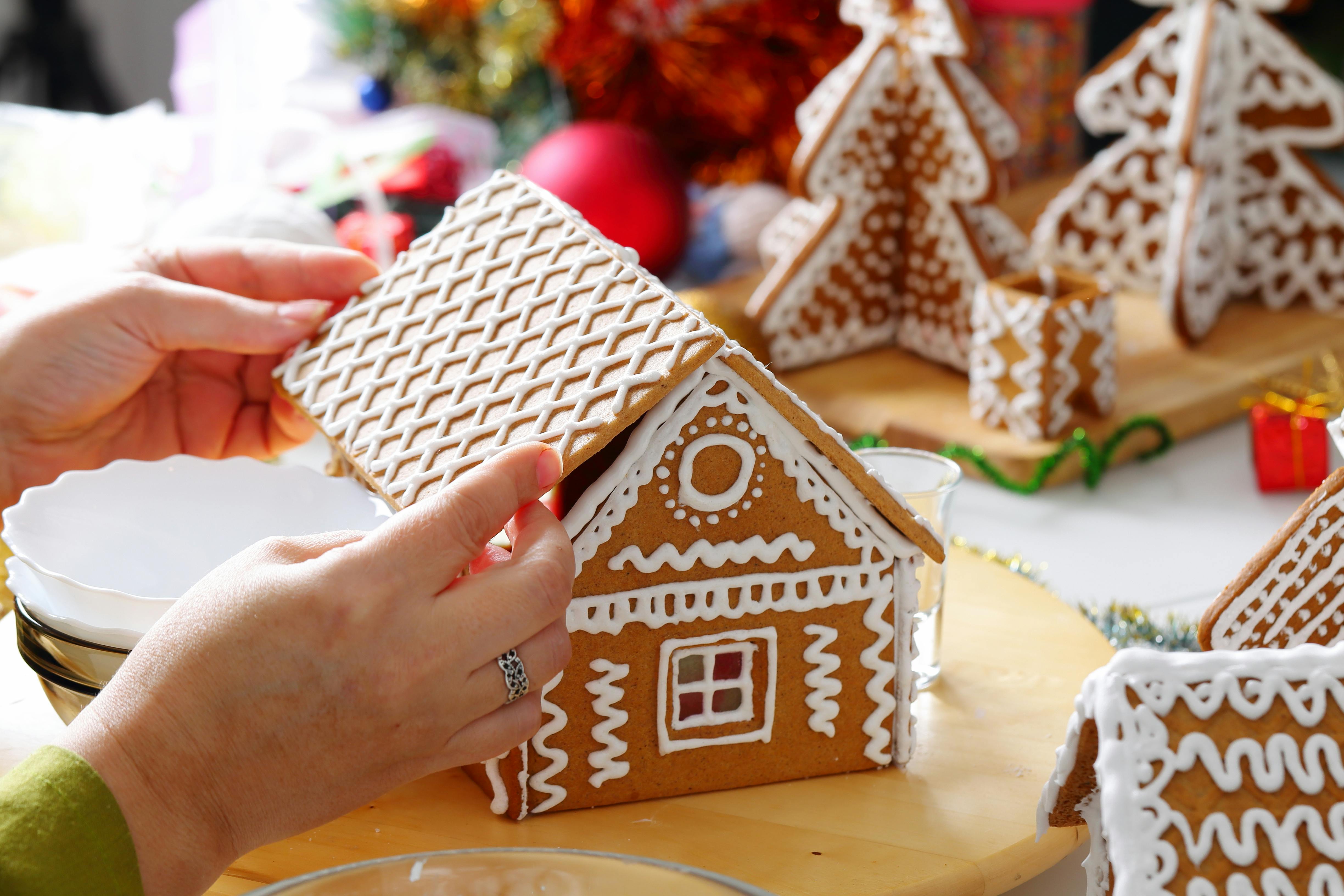 A person decorating a gingerbread house.