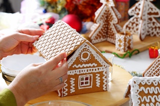 A person decorating a gingerbread house.