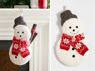 An Archie the Snowman Cozy Teddy Stocking hanging from a mantel and on a grey background