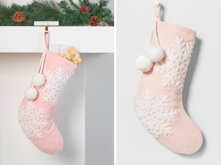 A Wondershop Velvet Christmas Stocking with Snowflakes hanging from a mantel and on a grey background