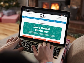 A person using a laptop, looking at the page of deals on the Christmas Tree Shops website.