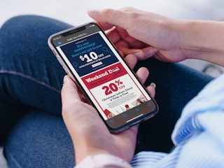 A person looking at their phone displaying an email from Christmas Tree Shops with coupons.