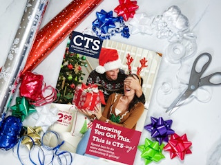 A Christmas Tree Shops weekly ad flyer on a table with some gift wrapping supplies