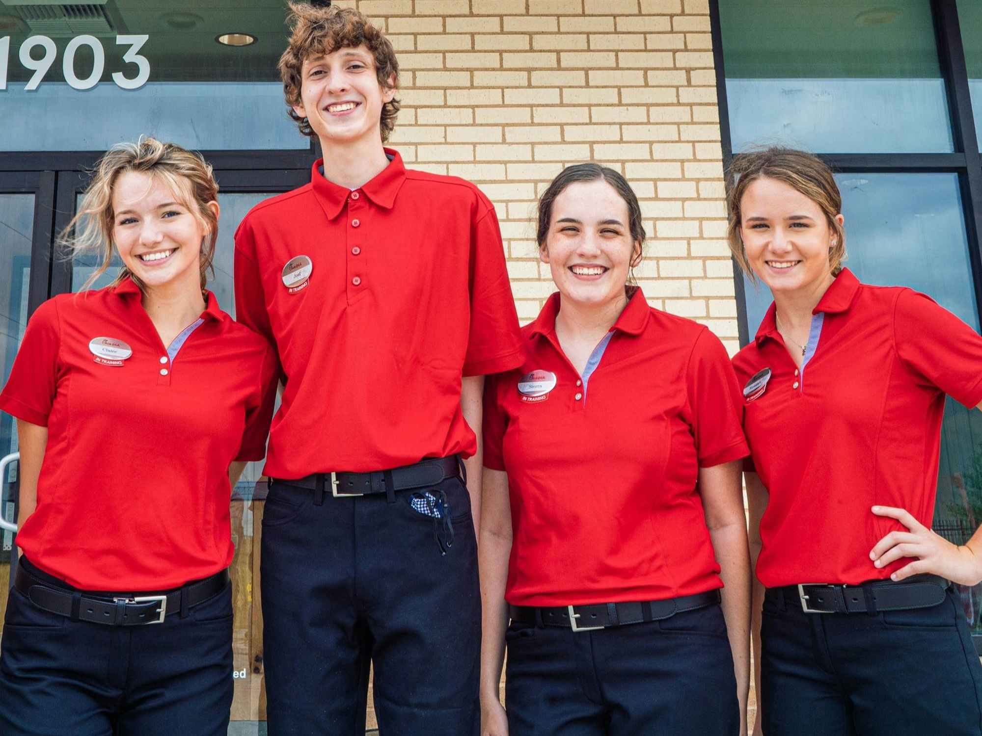 chick fil a team members standing together while smiling 