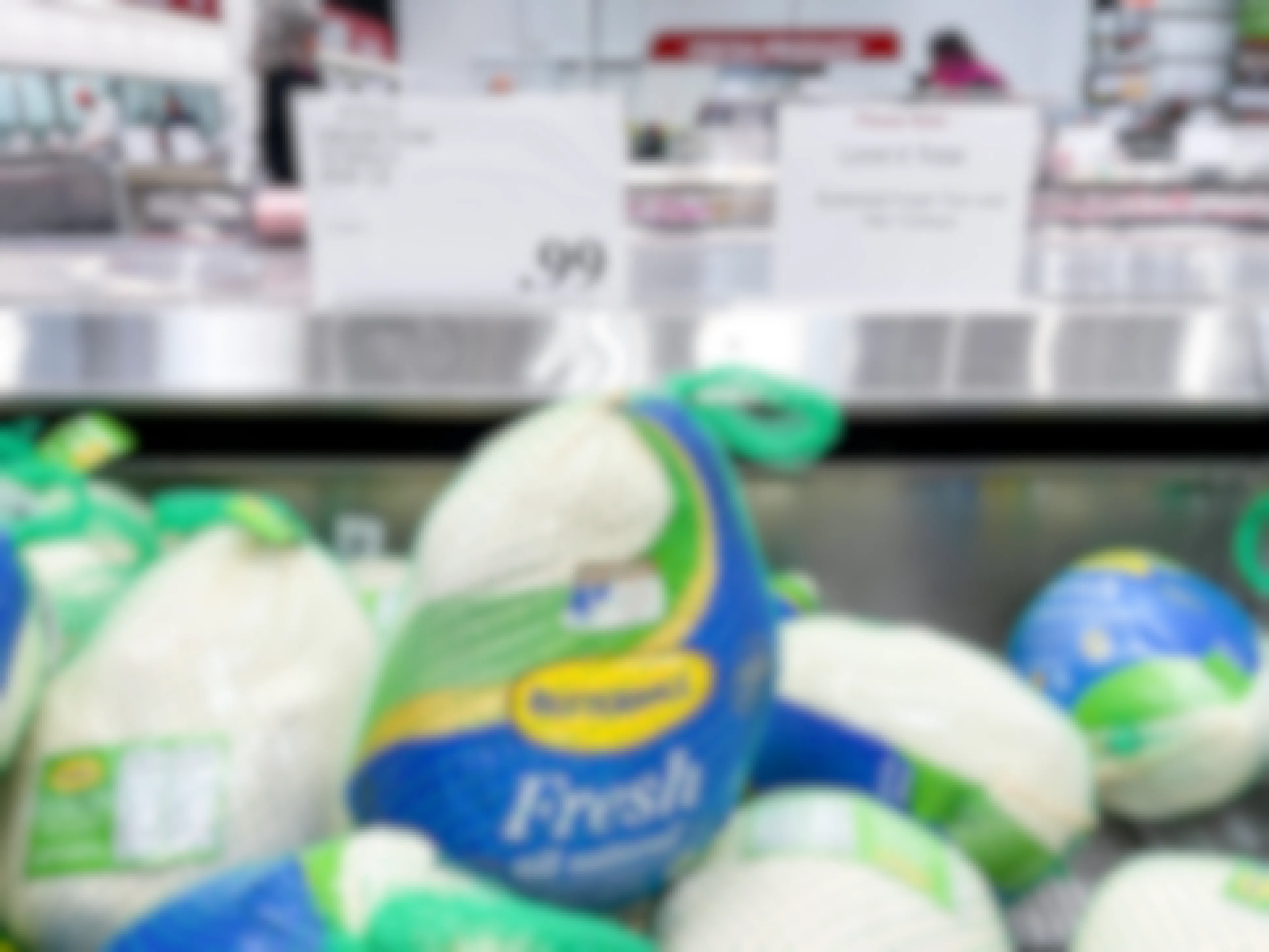 Whole Fresh Butterball turkeys in the refrigerated meat section of Costco with a sign showing them to be 99 cents per pound and another sign that reads, "Please Note, Limit 5 Total, Butterball fresh tom and hen turkeys