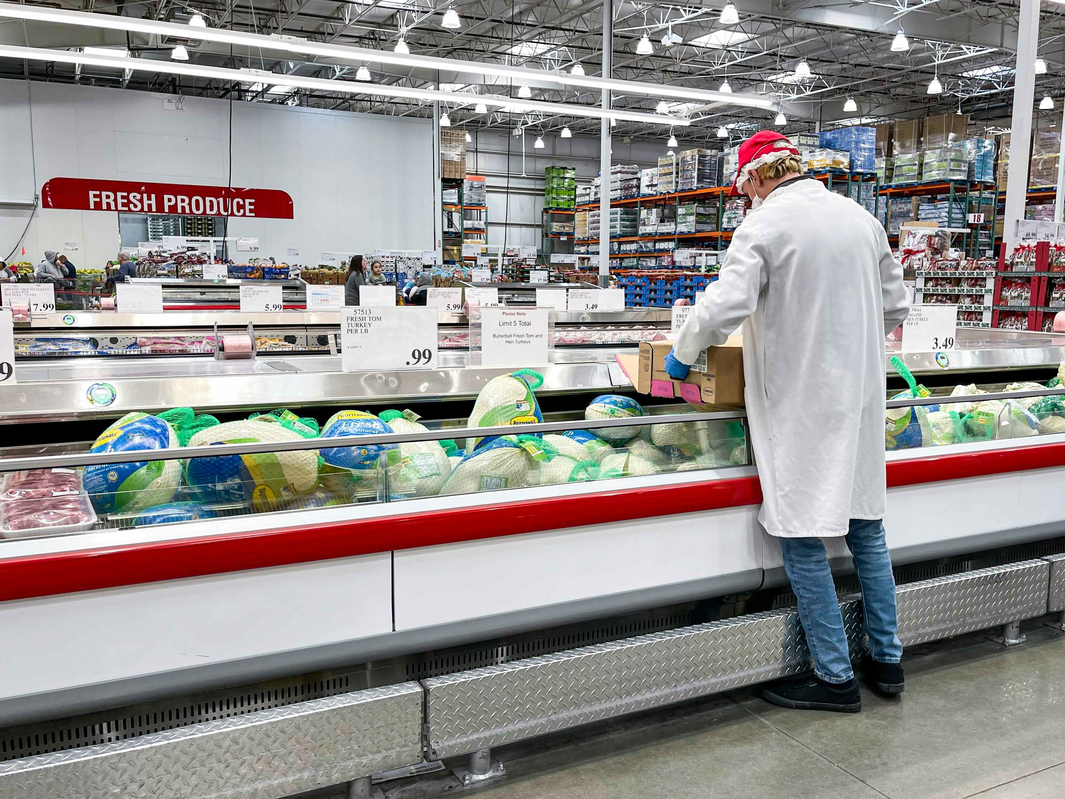 A Costco employee stocking Whole Fresh Butterball turkeys in the refrigerated meat section of Costco