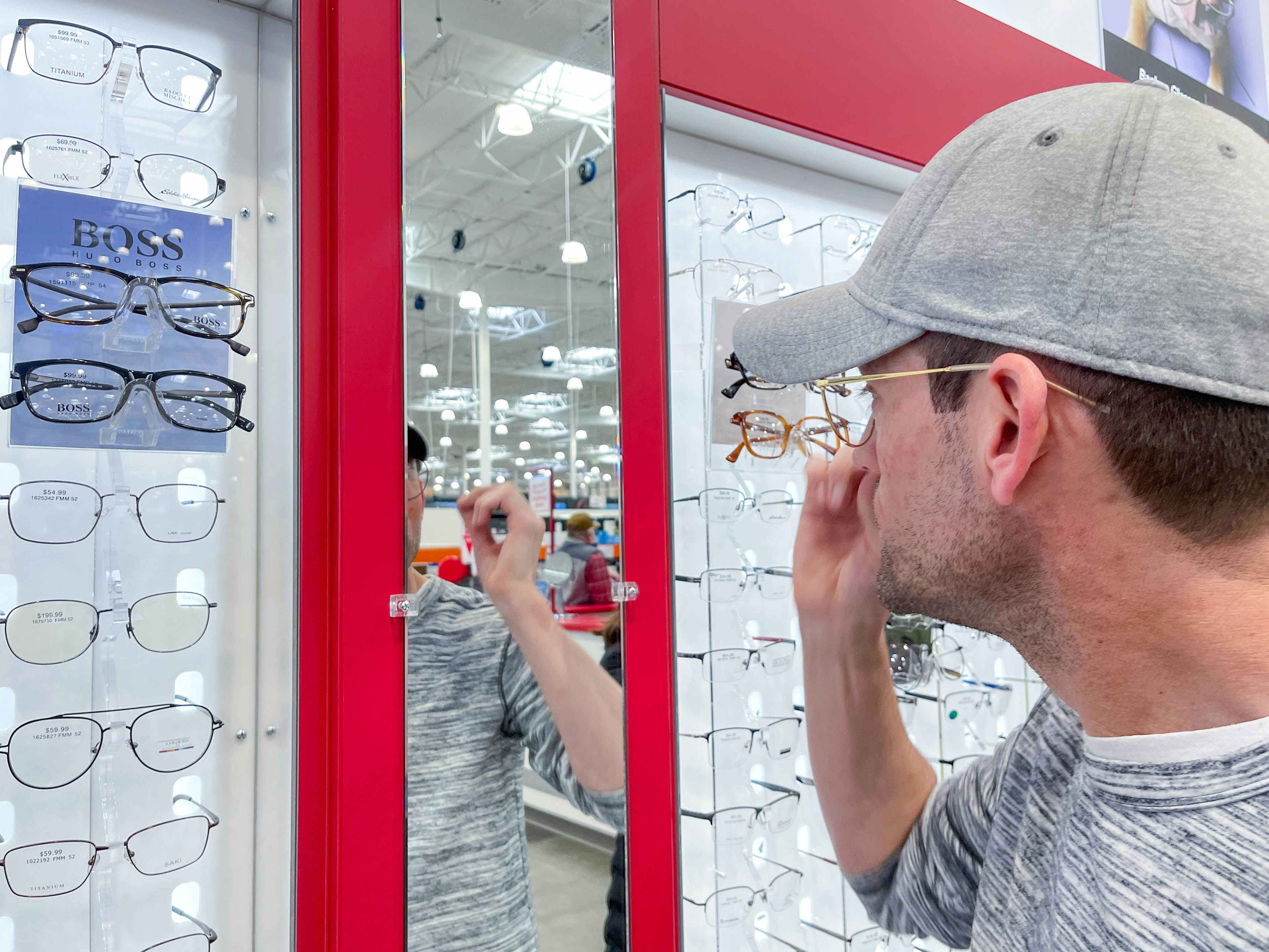 a man looking at costco optical eyeglasses on display