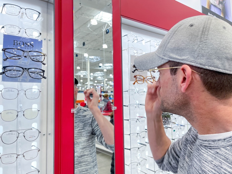 a man looking at costco optical eyeglasses on display