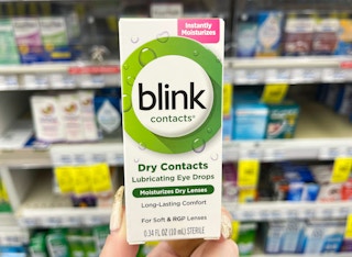 hand holding blink contacts in front of shelf