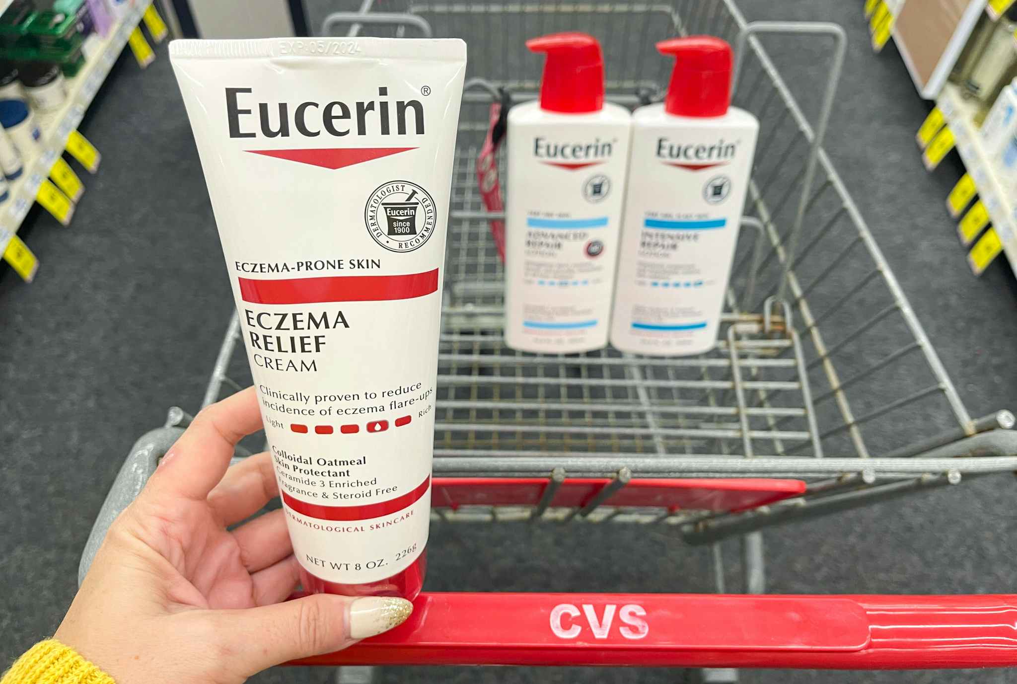 hand holding eucerin lotion in front of cvs cart