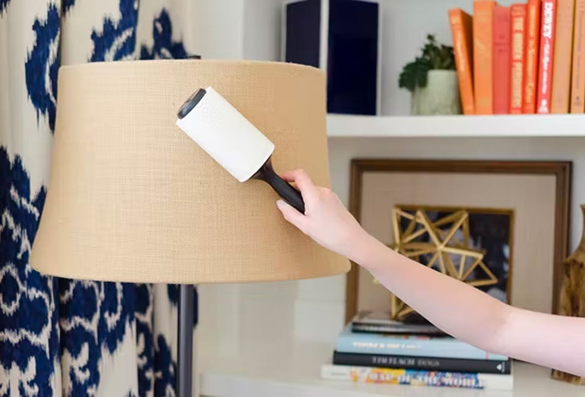 A person using a lint roller to clean a lampshade