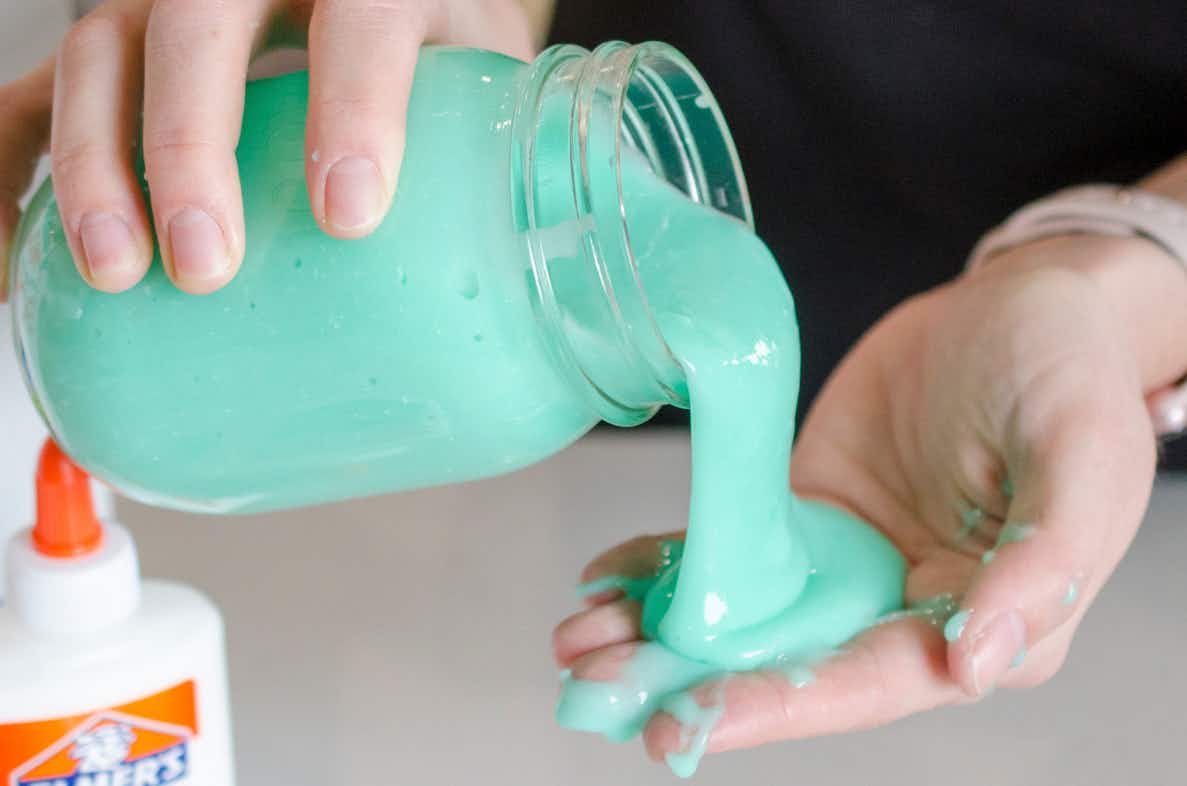 A person pouring homemade slime from a mason jar into their hand.