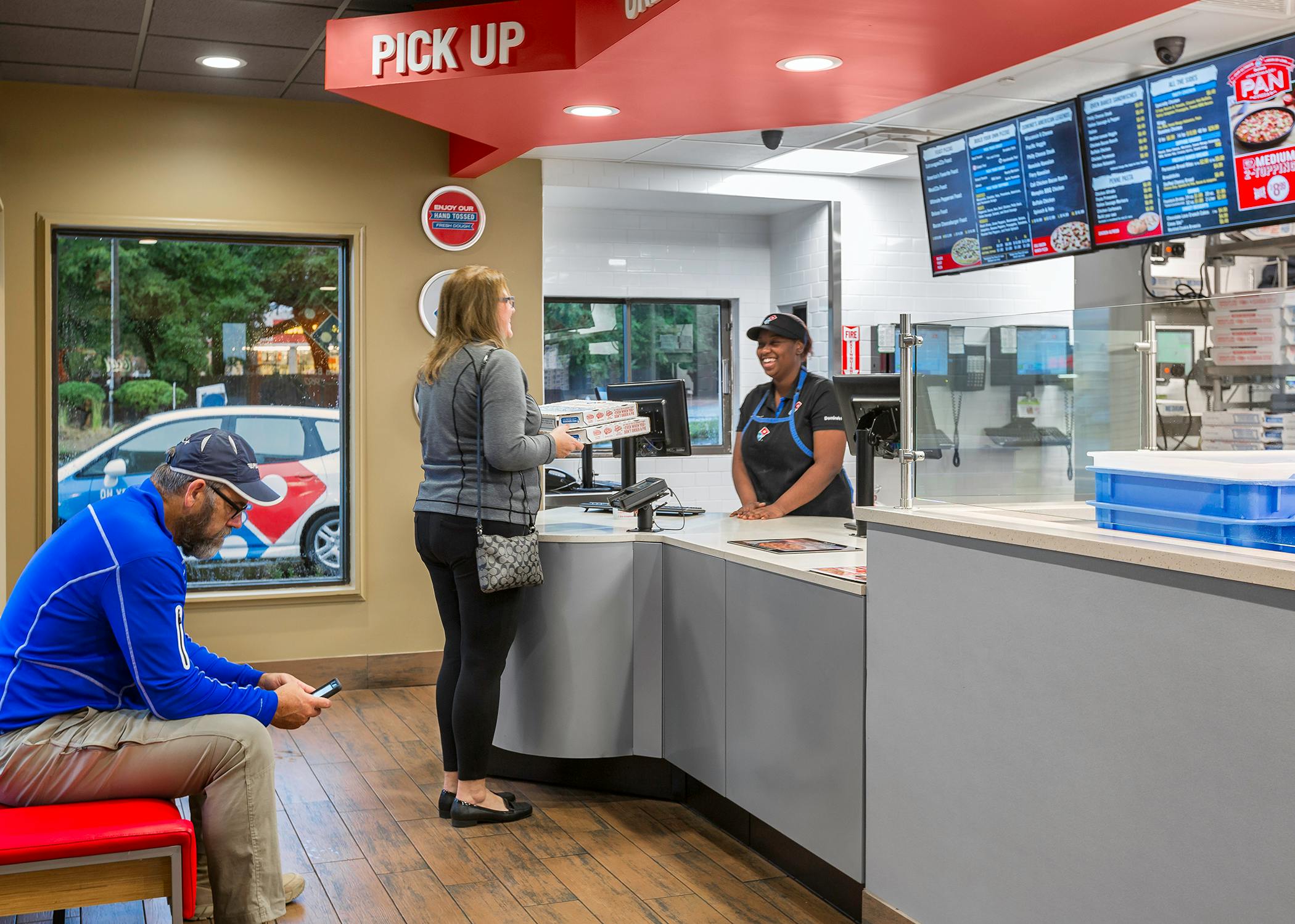 A person standing at the Domino's counter, talking to an employee