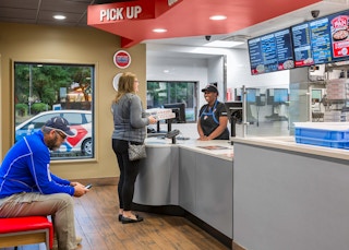 A person standing at the Domino's counter, talking to an employee