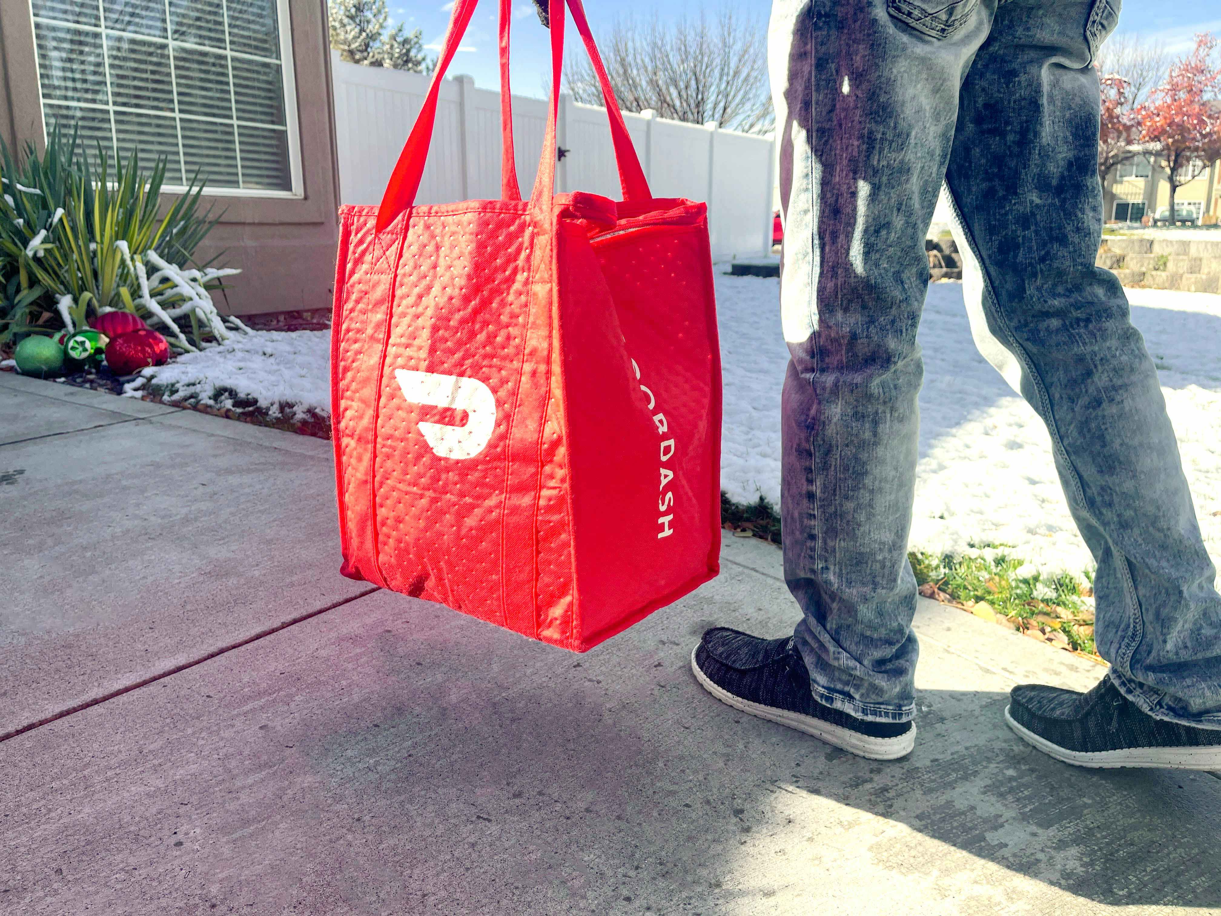 person walking while holding Doordash food delivery bag 