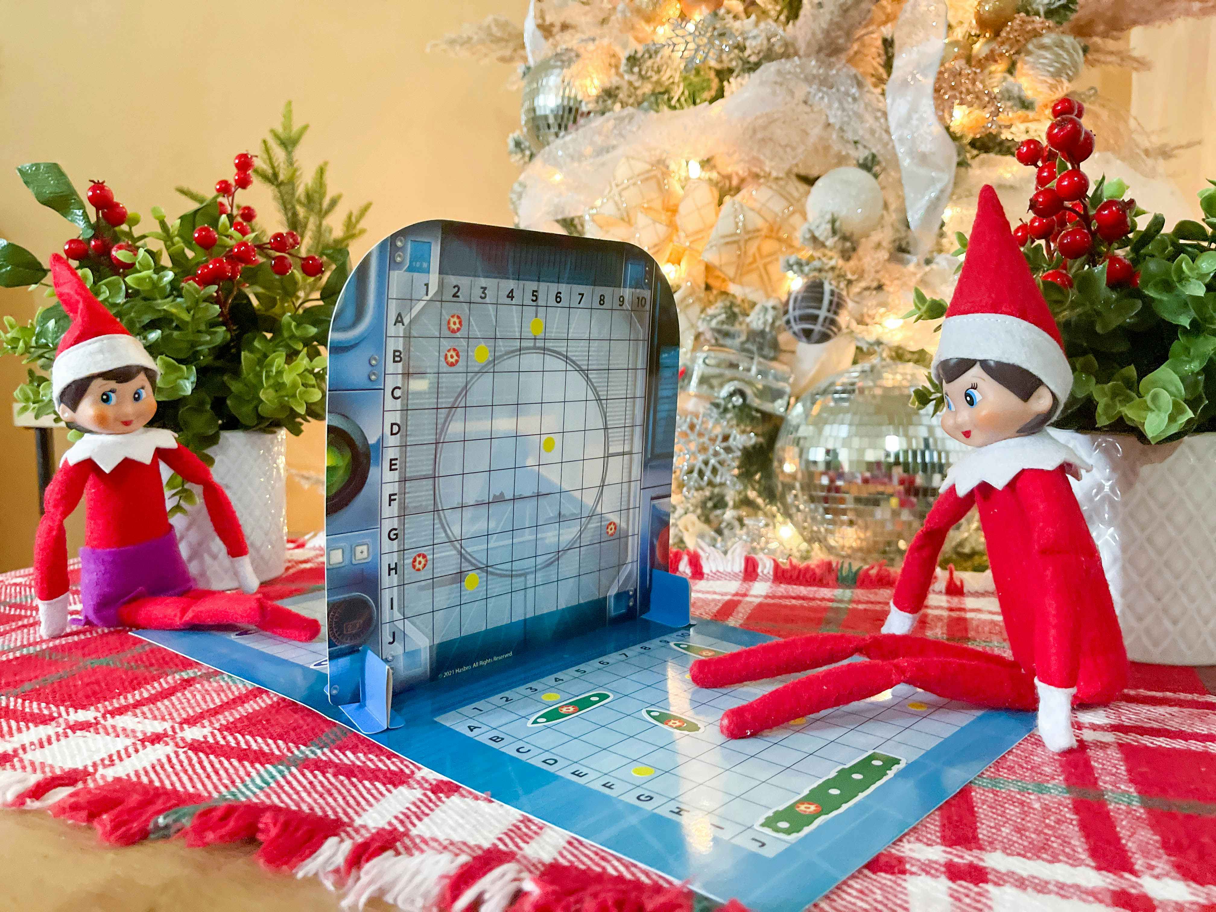 two elf on the shelf dolls playing a game of battleship 