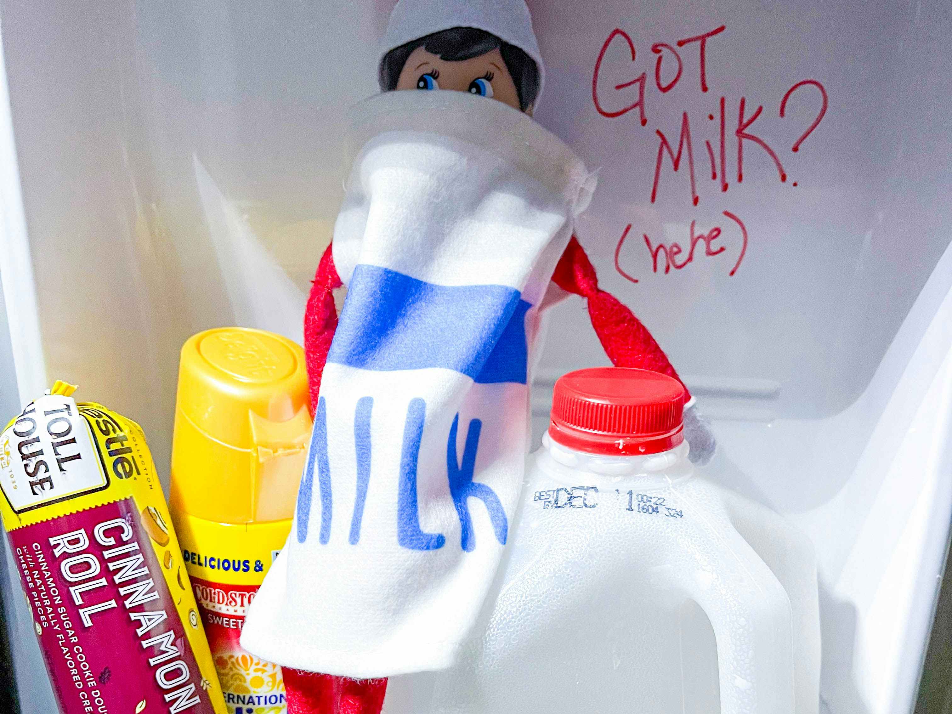an elf on the shelf doll dressed like milk in a fridge drawer 