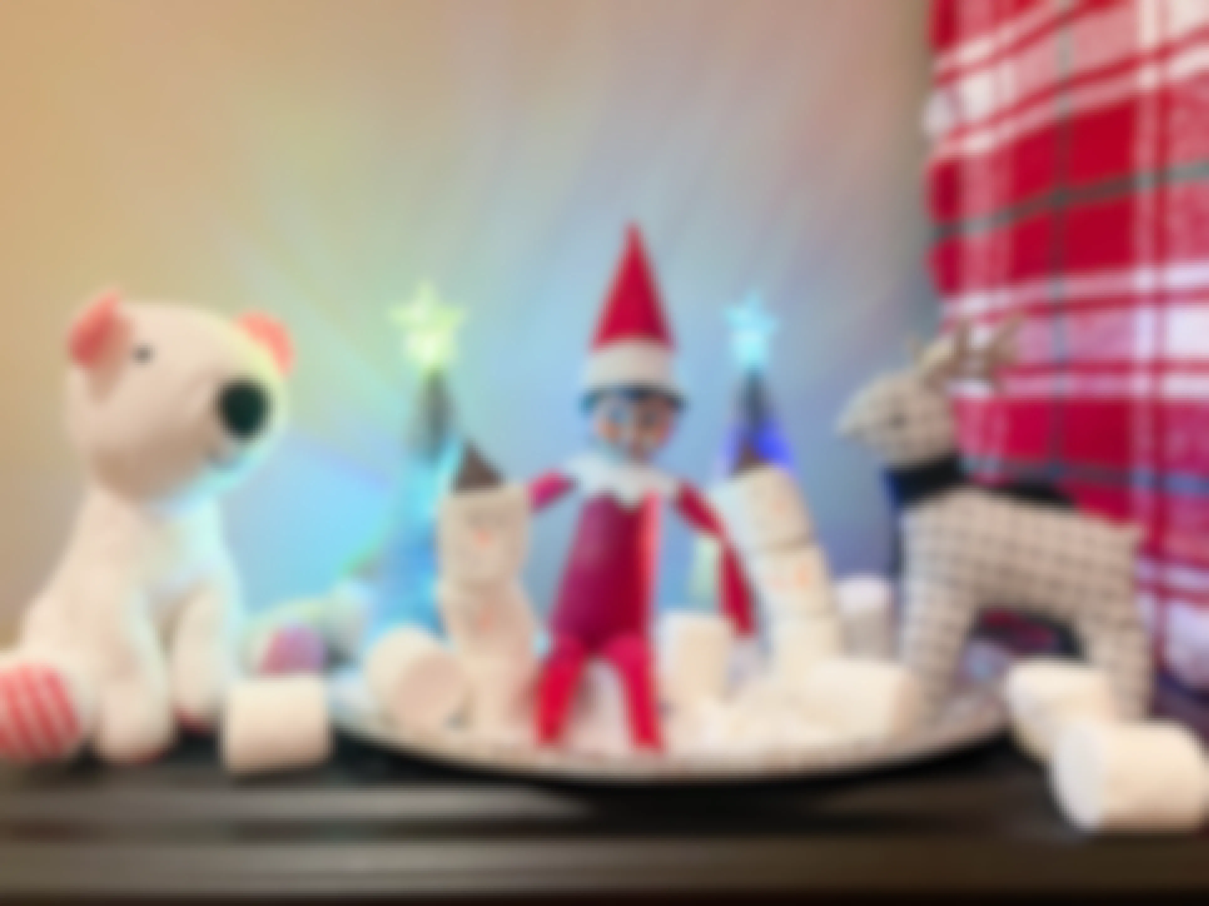 elf on the shelf doll next to marshmellow snowman next to studded animals 