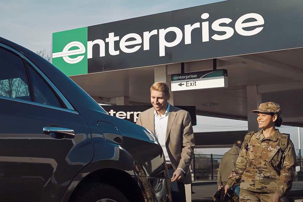 An Enterprise employee showing a vehicle to someone in military uniform