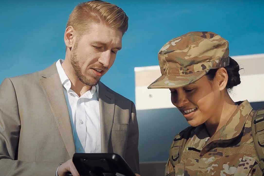 An Enterprise employee showing a vehicle to someone in military uniform