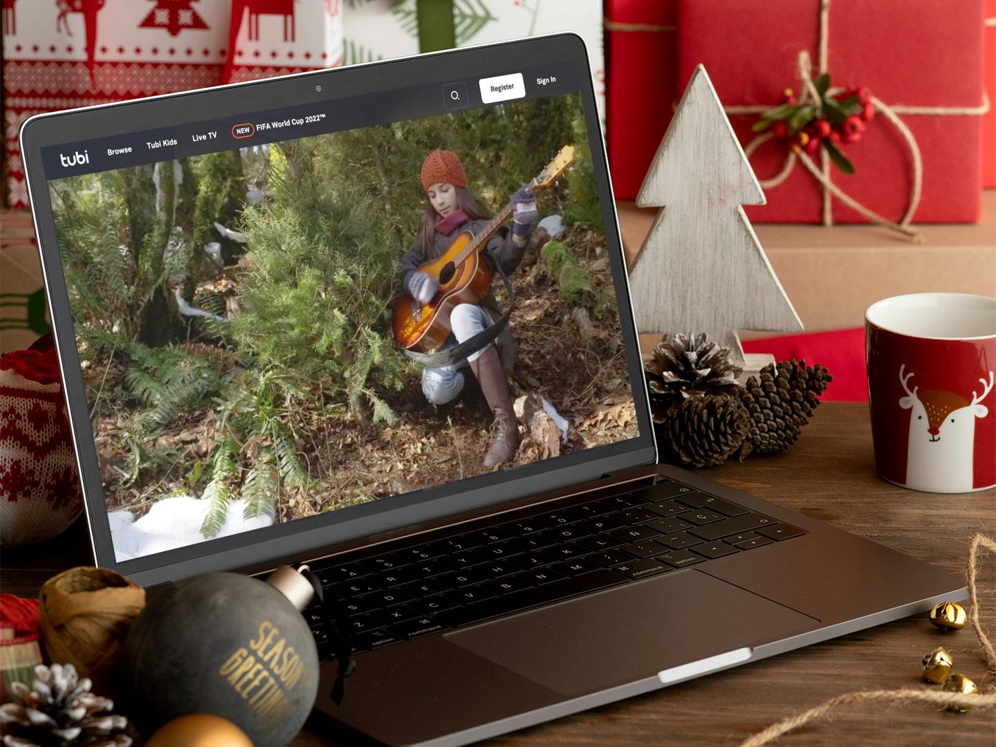 person watching holiday movie on laptop with christmas decor