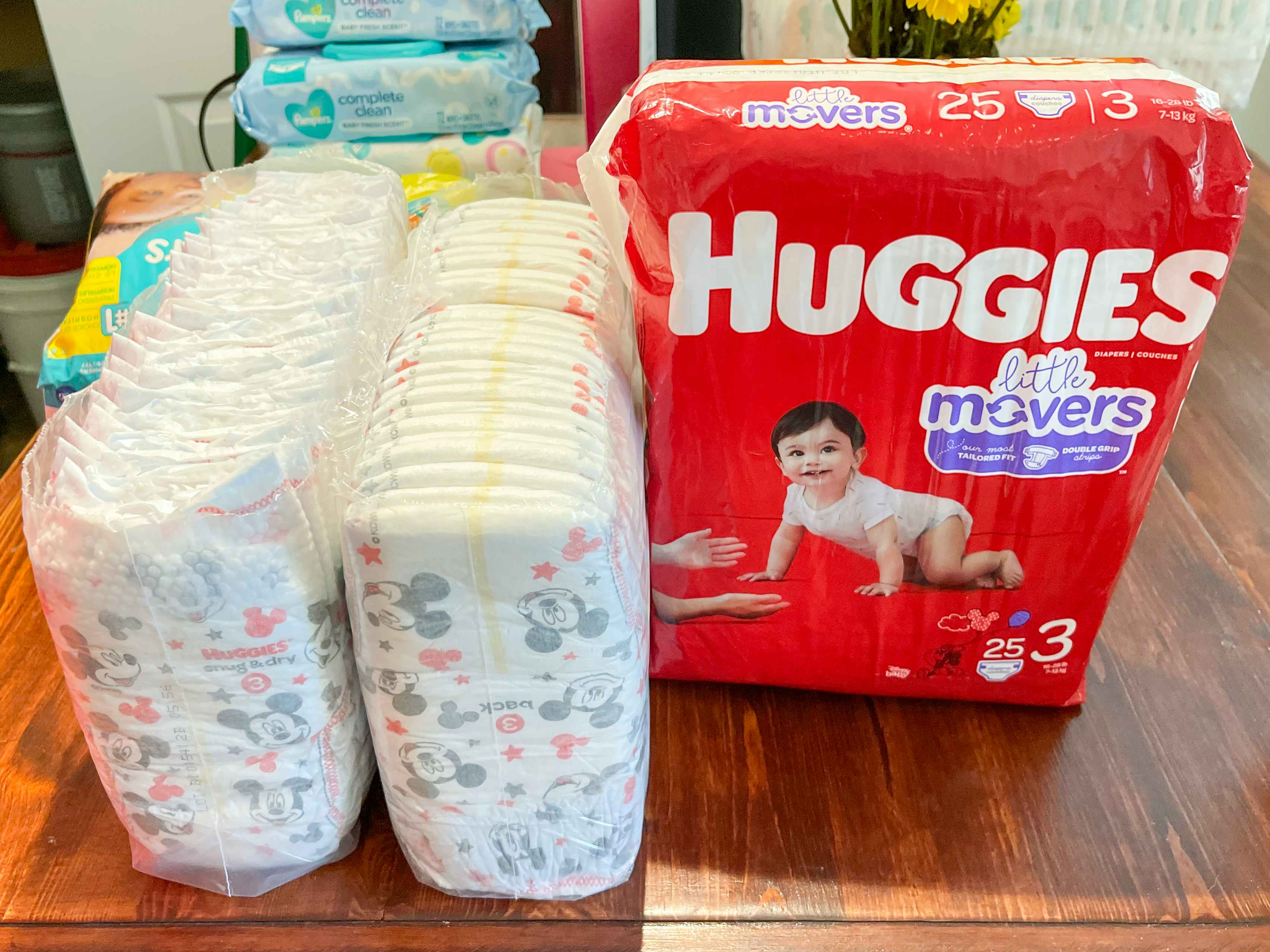 Huggies and pampers diapers, some packs open sitting on a kitchen table
