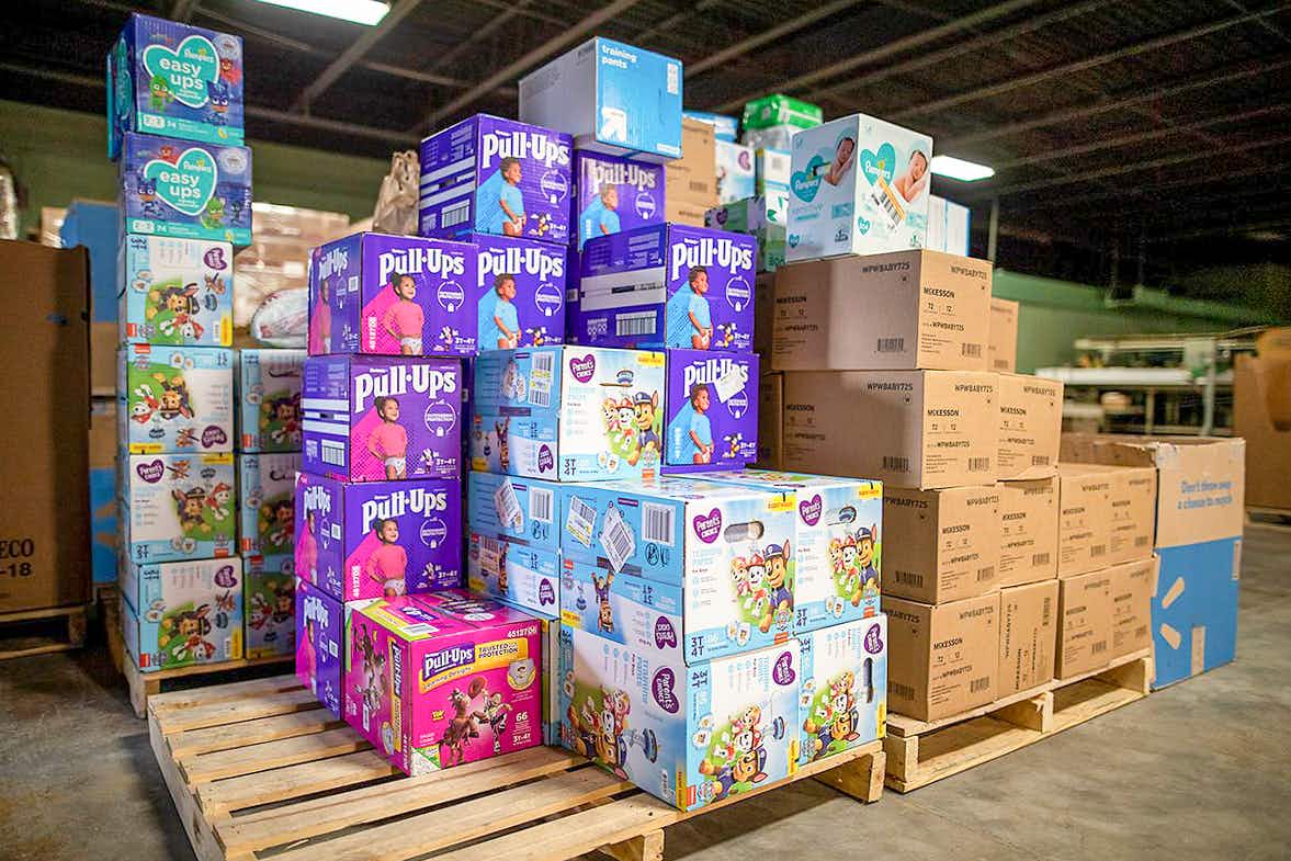 A large stack of diapers on pallets inside a warehouse.