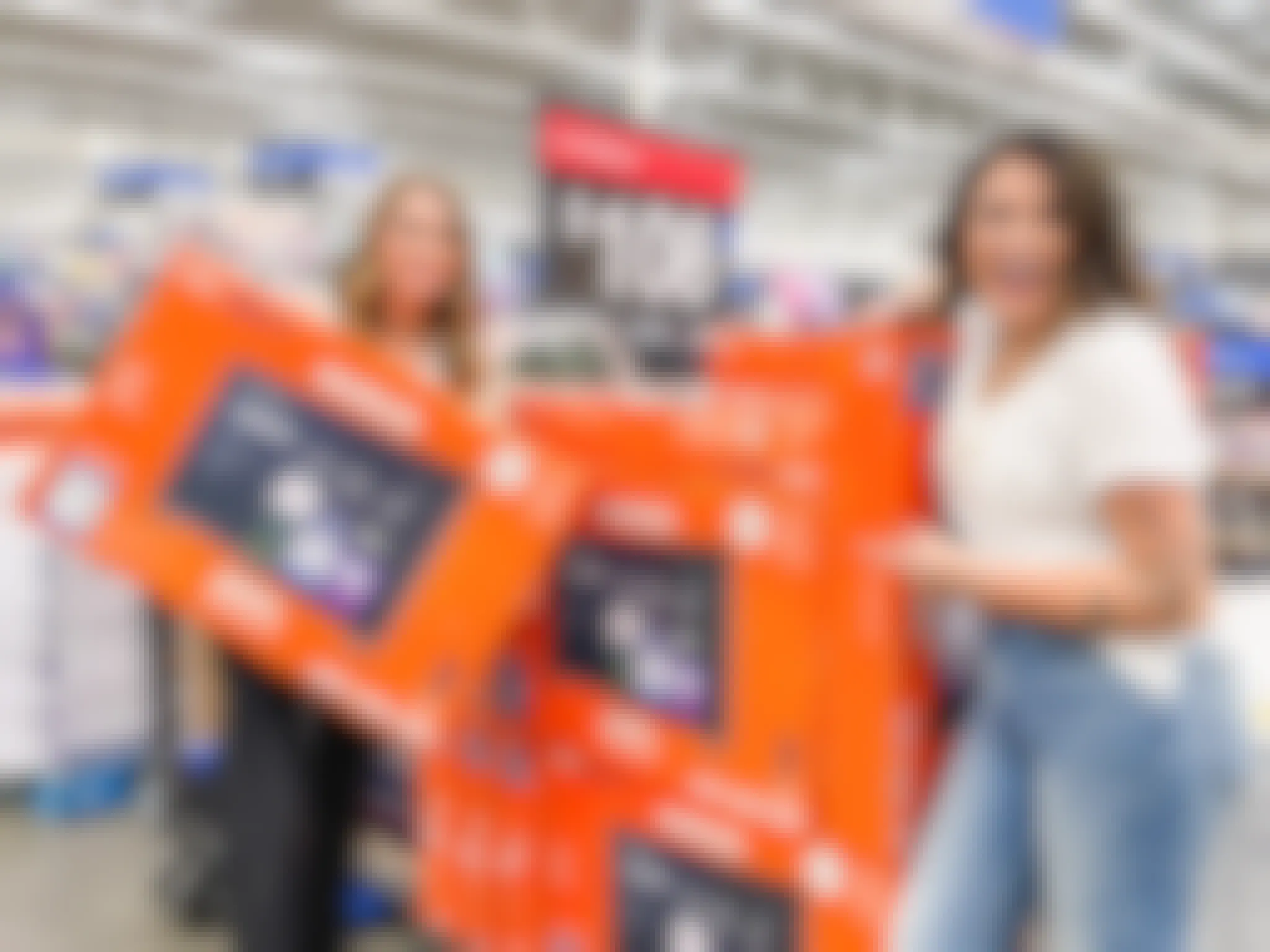 woman pointing at TV box and another woman holding a TV box at Walmart