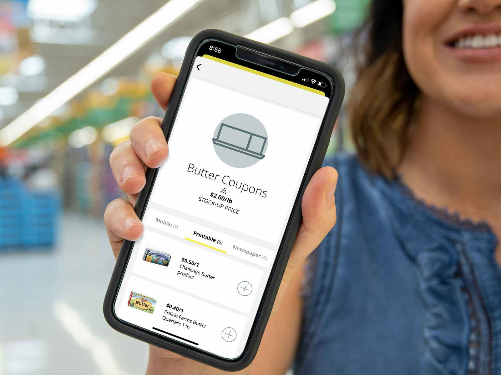 A person holding up a cell phone displaying the butter coupons on the KCL mobile app