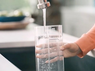 person rinsing keurig coffee maker water tank in sink