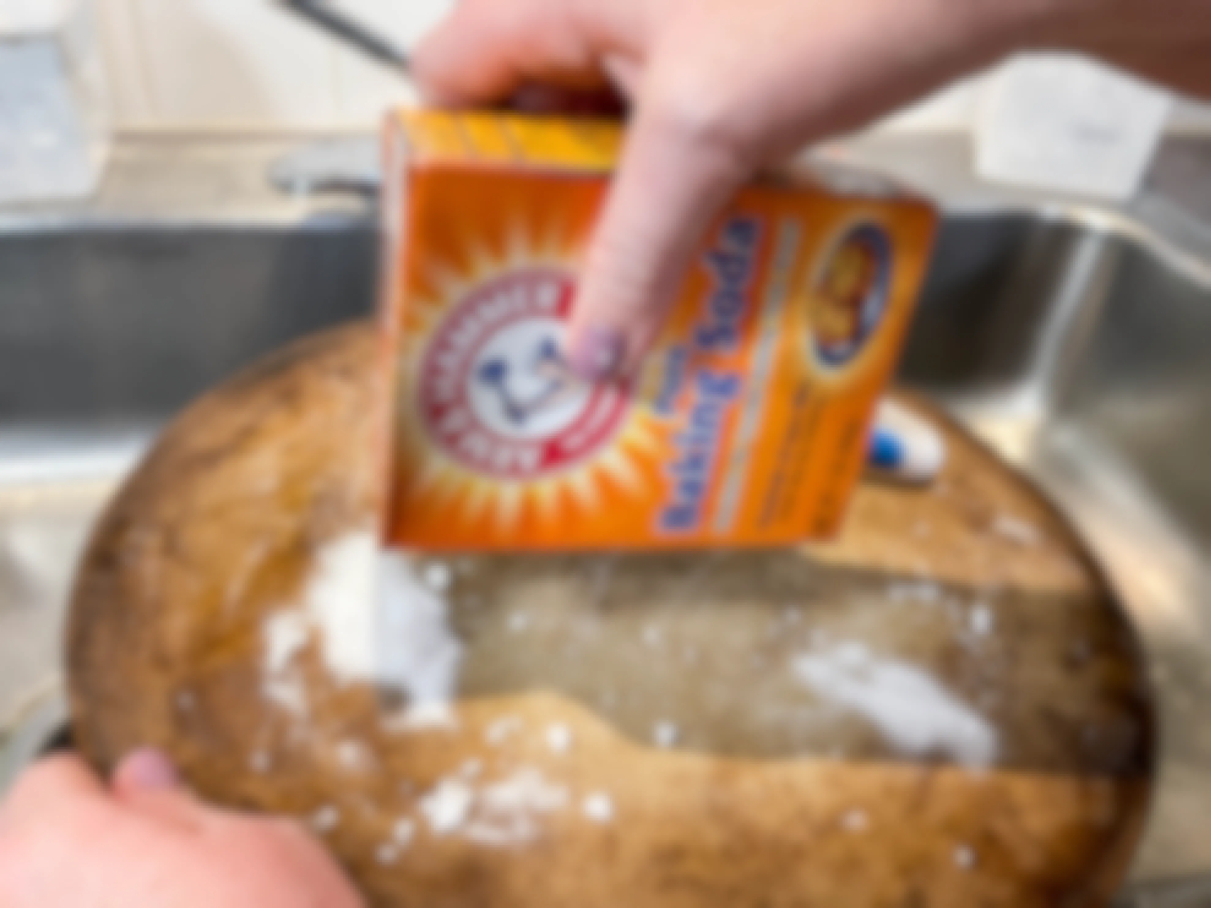 a person sprinkling baking soda onto a pizza stone 