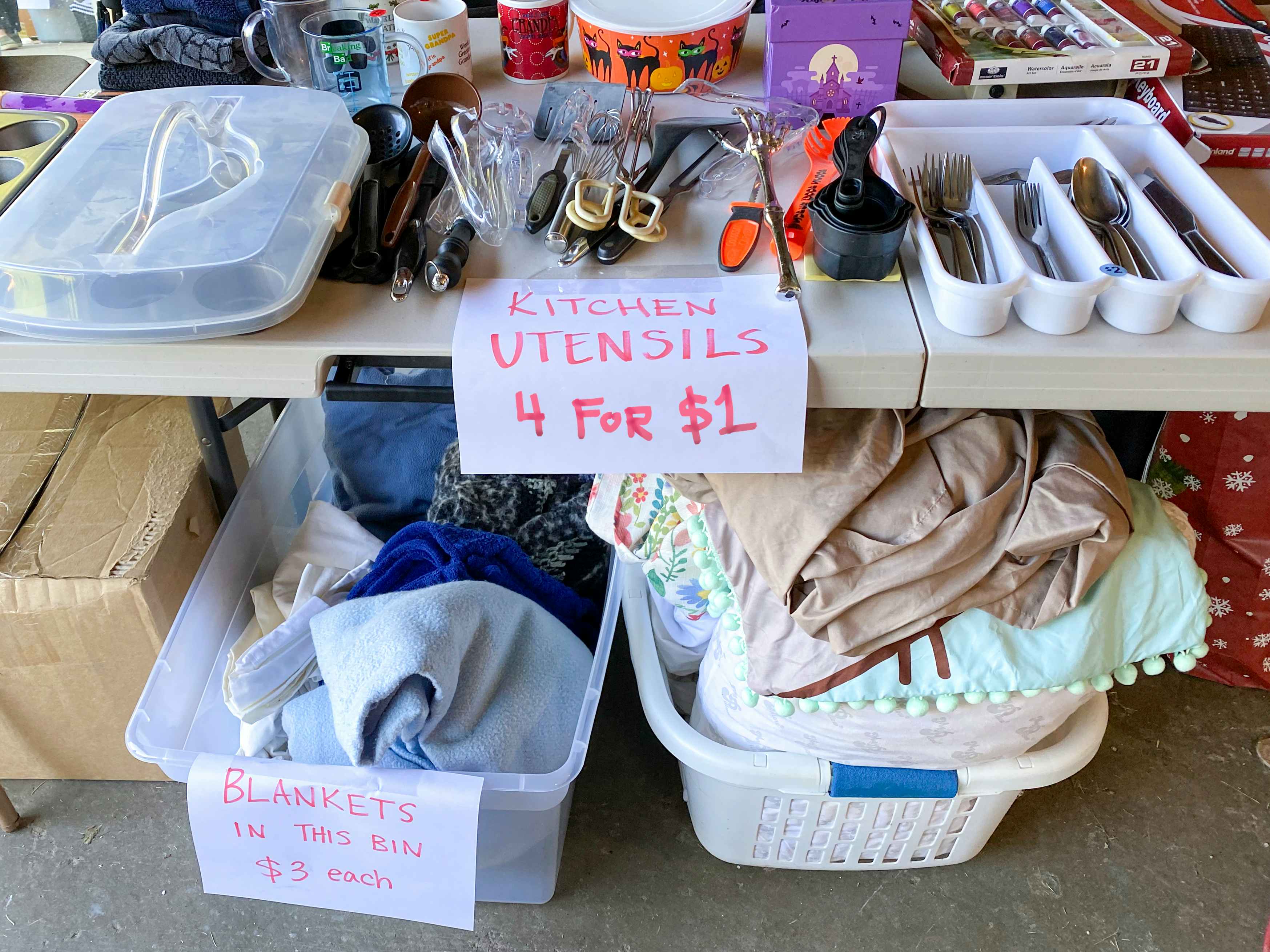 Tables of items for sale at a garage sale and signs advertising their prices