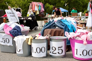 Bins at a garage sale with price signs on the going up in 25 cent increments 