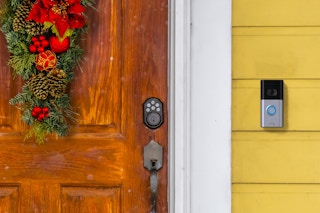 A Ring doorbell outside of a front door that is decorated for Christmas