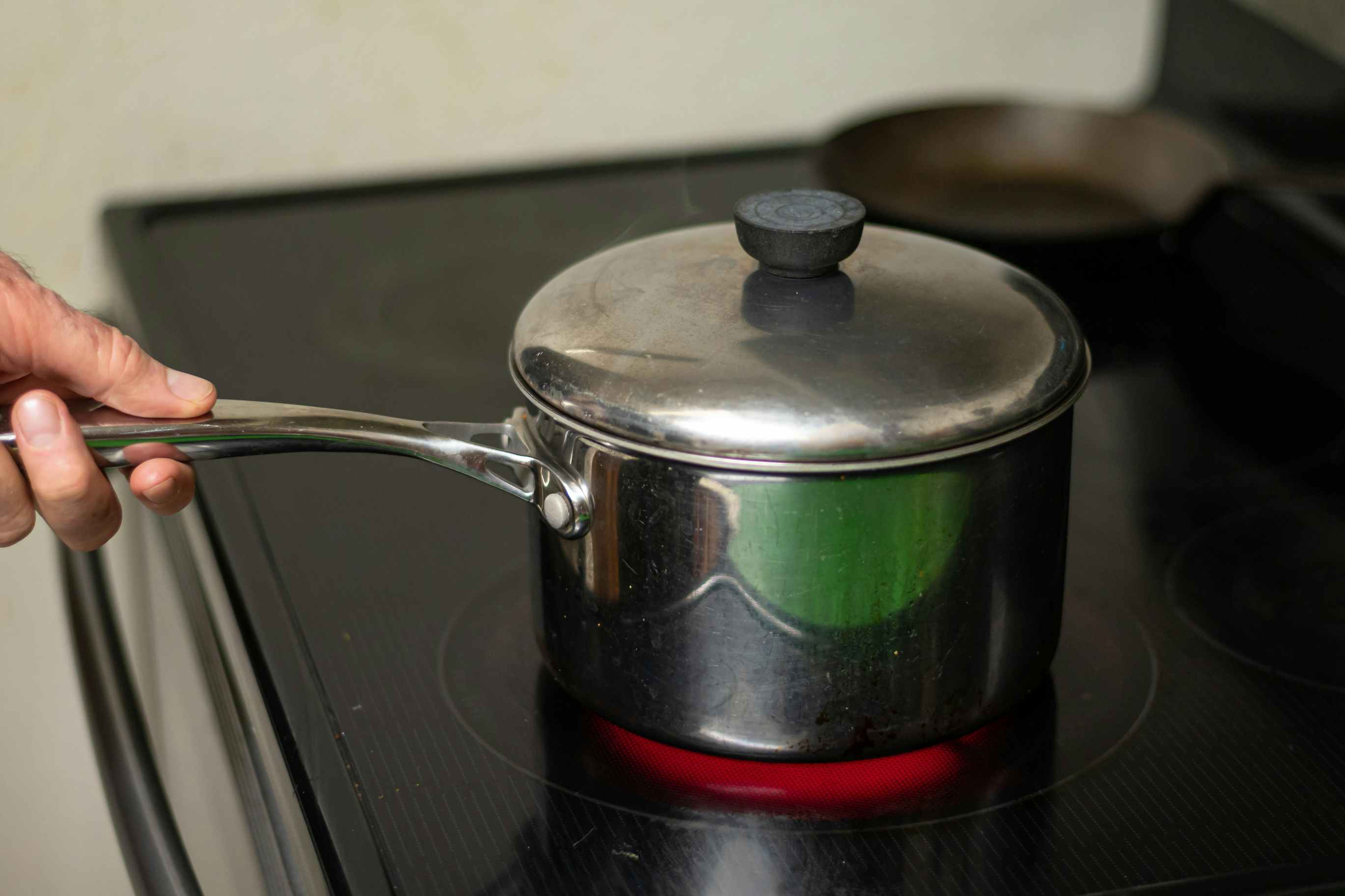 A saucepan on a stovetop being used to heat up popcorn