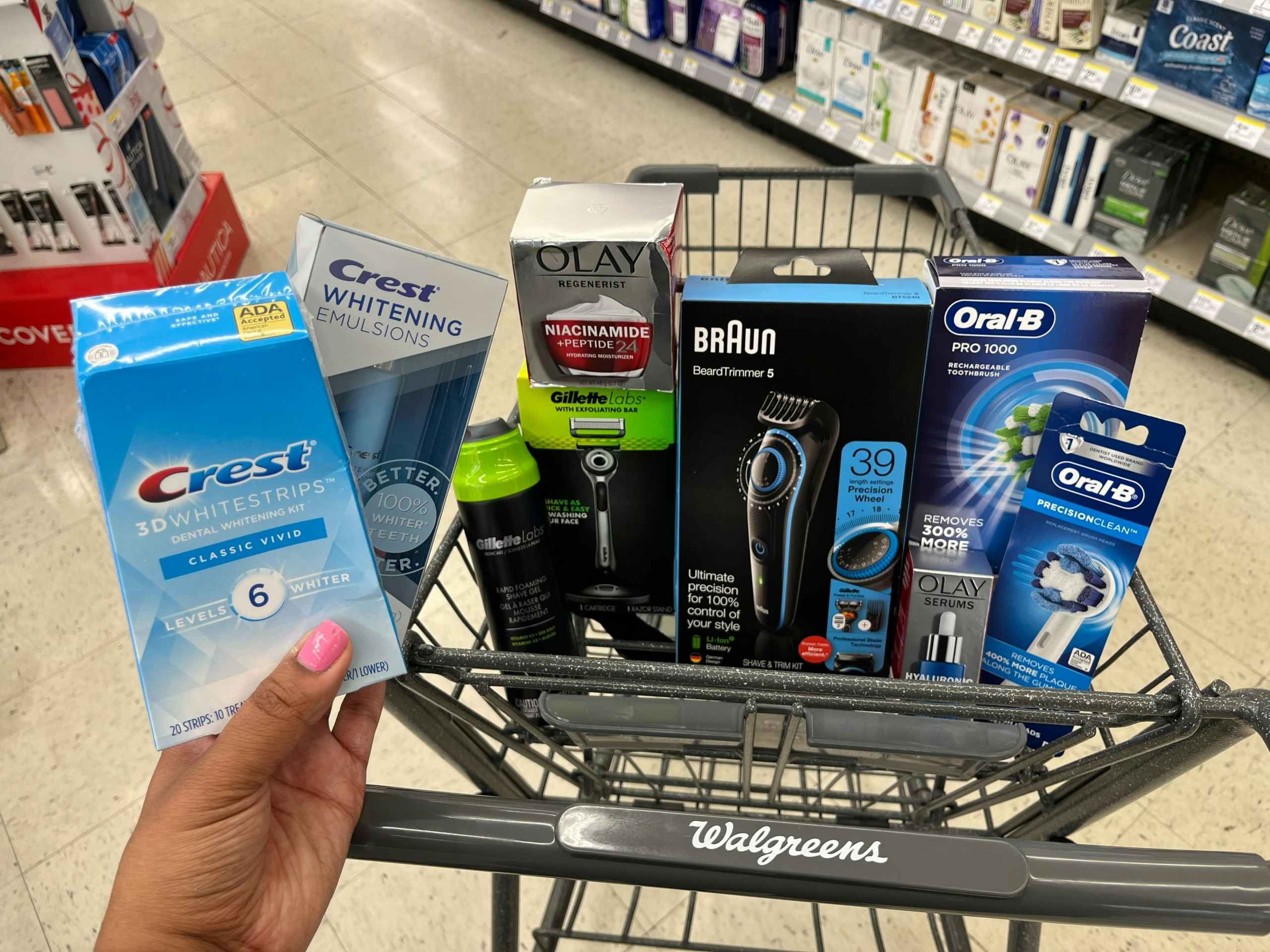 hand holding crest whitening strips in front of basket containing p&g products