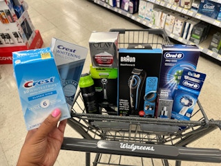 hand holding crest whitening strips in front of basket containing p&g products