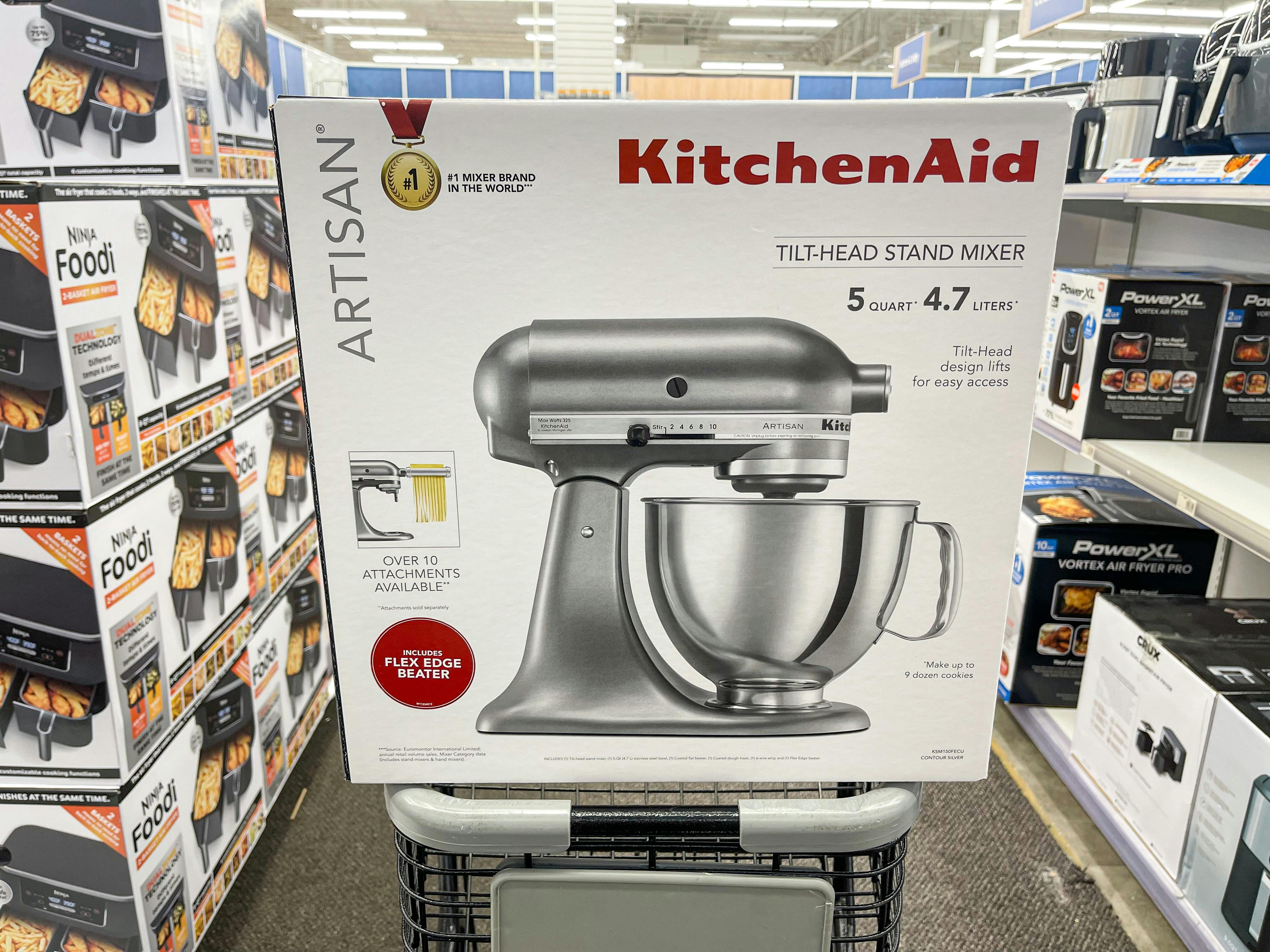 A KitchenAid Stand alone mixer sitting on the edge of a shopping cart.