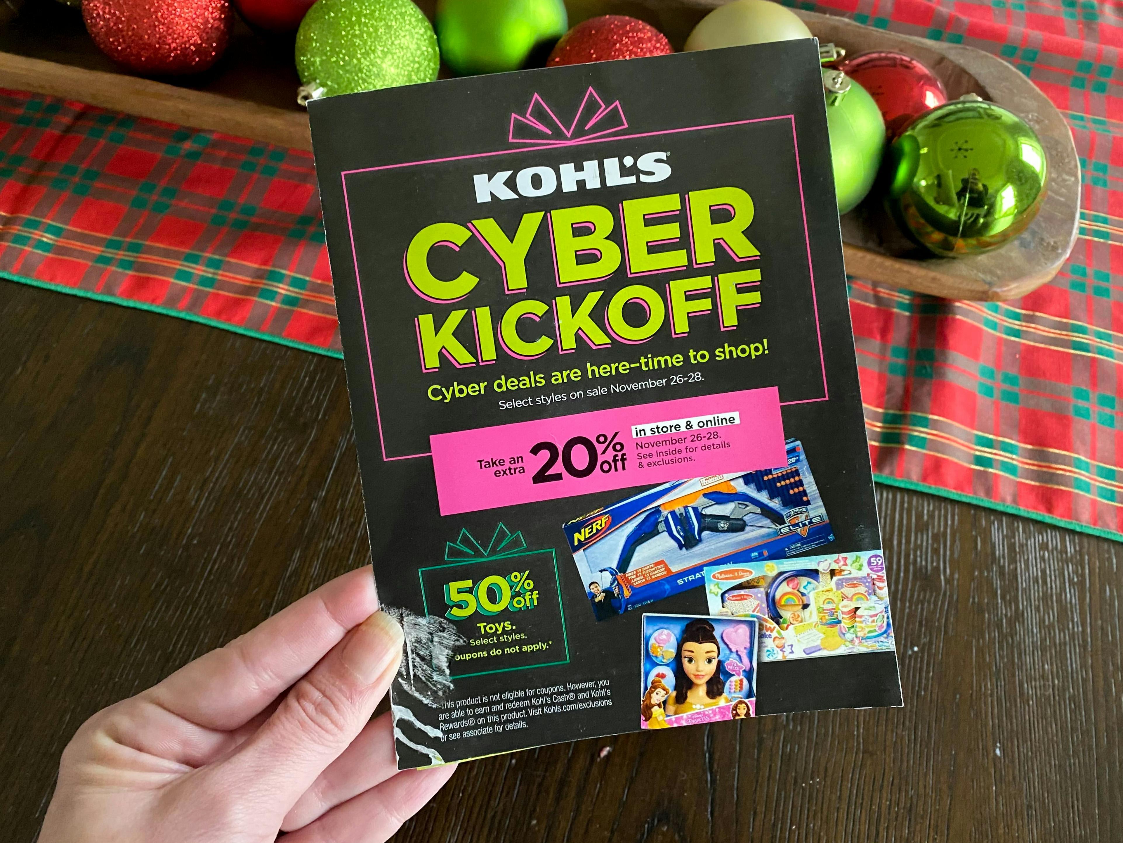 A person holding a Kohl's Cyber Monday 2022 advertisement in front of a table